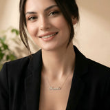 Damă cu păr lung negru prins lejer purtând lănțișor argint 925 rodiat Ionela pe stern peste sacou negru desfăcut, interior cald cu plante