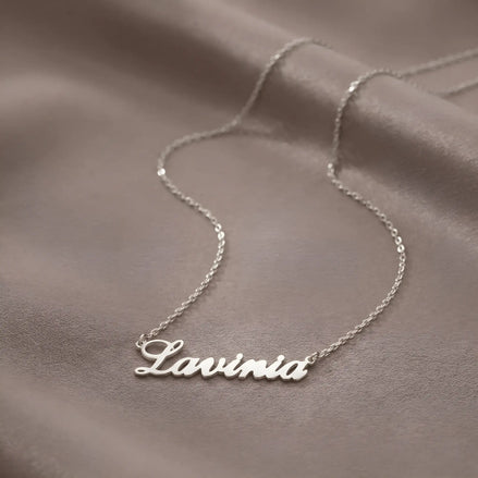 Lănțișor argint 925 rodiat personalizat cu numele Lavinia decupat în scriere cursivă elegantă cu L larg pe drapaj satin maroniu mătăsos, lanț subțire alb-platinat