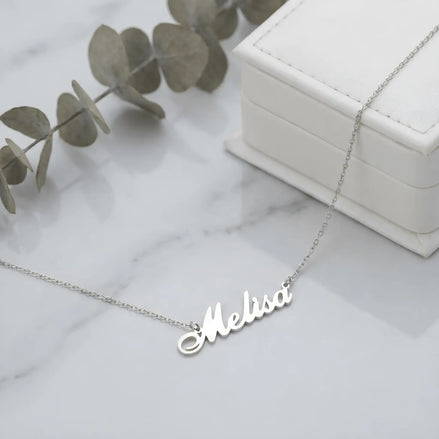 Lănțișor argint 925 rodiat cu numele Melisa, pandantiv decupat 38.5x10 mm font cursiv, lanț anchor 46 cm, lângă cutie cadou albă