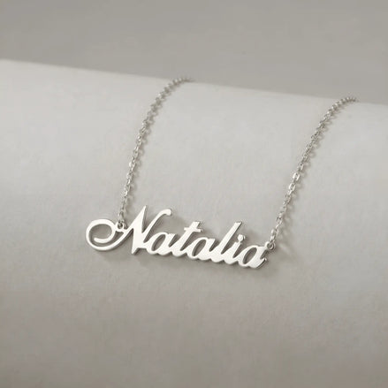 Lănțișor argint 925 rodiat cu numele Natalia, pandantiv decupat 42x10 mm font cursiv inițiala N cu diagonală descendentă, lanț anchor 46 cm pe bust expozițional ivory mat