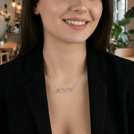 Damă cu păr lung negru bob mediu purtând lănțișor argint 925 rodiat Natalia pe stern peste sacou negru desfăcut, cafenea cu plante și lumini ambient