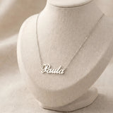 Lănțișor argint 925 rodiat personalizat cu numele Paula decupat în scriere cursivă elegantă cu P și coadă caligrafică pe bust display textil natural pe textil bej, lanț subțire alb-platinat