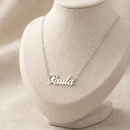 Lănțișor argint 925 rodiat personalizat cu numele Paula decupat în scriere cursivă elegantă cu P și coadă caligrafică pe bust display textil natural pe textil bej, lanț subțire alb-platinat