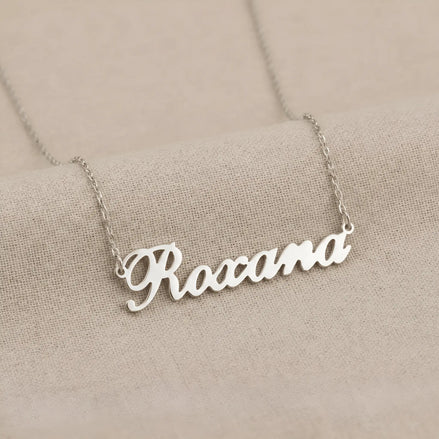 Lănțișor argint 925 rodiat personalizat cu numele Roxana decupat în scriere cursivă elegantă pe lanț subțire alb-platinat, ambianță textilă caldă bej
