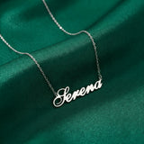 Lănțișor argint 925 rodiat personalizat cu numele Serena decupat în scriere cursivă elegantă cu S ondulat pe drapaj satin verde smarald, lanț subțire alb-platinat