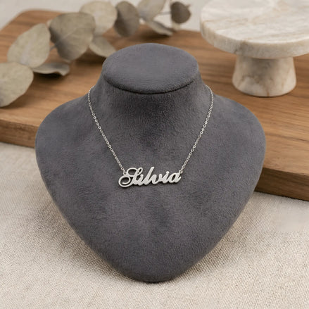 Lănțișor argint 925 rodiat personalizat cu numele Silvia decupat în scriere cursivă elegantă cu S ondulat pe bust display gri velvet pe lemn cu eucalipt, lanț subțire alb-platinat