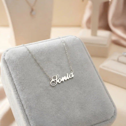 Lănțișor argint 925 rodiat personalizat cu numele Sonia decupat în scriere cursivă elegantă cu S ondulat pe cutie velvet gri în showroom, lanț subțire alb-platinat
