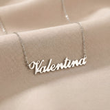 Lănțișor argint 925 rodiat cu numele Valentina, pandantiv decupat 51x10 mm font cursiv inițiala V cu două linii oblice, lanț anchor 46 cm pe textil satinat ivory cu pliuri delicate