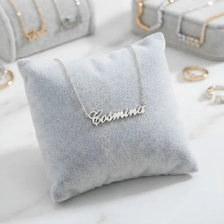 Lănțișor argint 925 rodiat personalizat cu numele Cosmina decupat în scriere cursivă elegantă pe pernuță gri velvet, ambianță jewelry display alb-marmorat