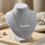 Lănțișor argint 925 rodiat cu pandantiv decupat textul caligrafic Cristina, expus pe bust gri velvet cu decor natural